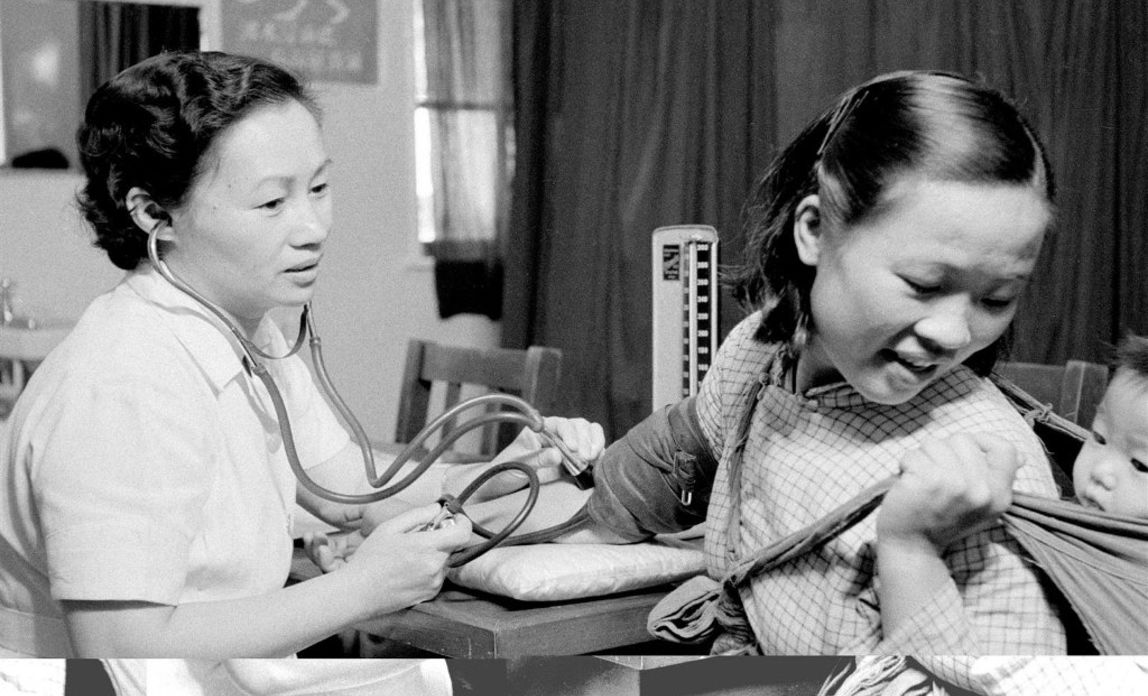 Hong Kong 1950: Eine Krankenschwester nimmt einer Mutter, die ihr Kind auf dem Rücken trägt, Blut ab. © UNICEF/UNI43153/Ling