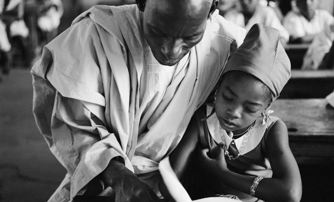 Nigeria 1963: Der Lehrer Mallam Germba Malunfashi hilft einer Schülerin, der achtjährigen Baraka, beim Lesen. © UNICEF/UNI41907/Bernheim